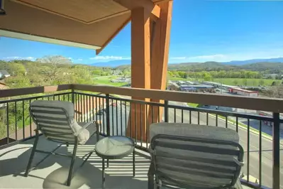 view of mountain and city from covered balcony with chairs
